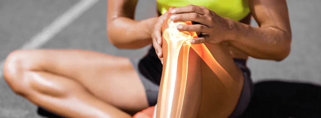 Female athlete sitting on track holding knee in pain, showcasing injury