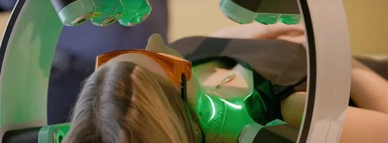 The Emerald green laser from Erchonia interface with hand pressing the start button and patient in the background.